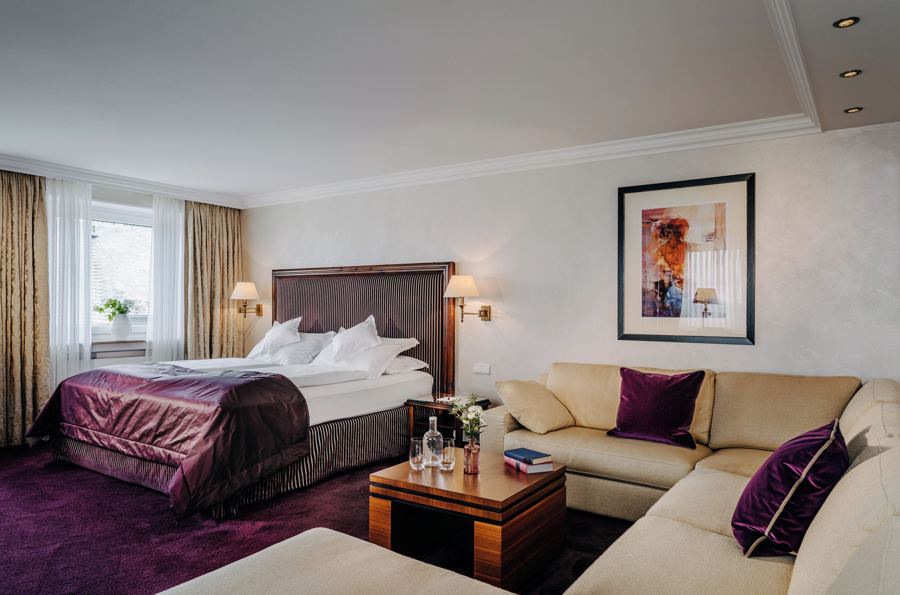 Ein Hotelzimmer mit einem Bett, einem Sofa, einem Couchtisch und einem Bild an der Wand.