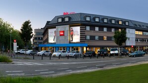 A modern hotel with a prominent 'ibis' sign, multiple parking spaces, and a well-maintained roadside. - ibis Aalst Centrum (Aalst)