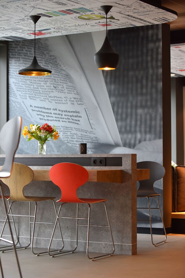 A modern bar area with a unique design, featuring a large menu wall, stylish pendant lighting, and a mix of metal and wooden chairs.