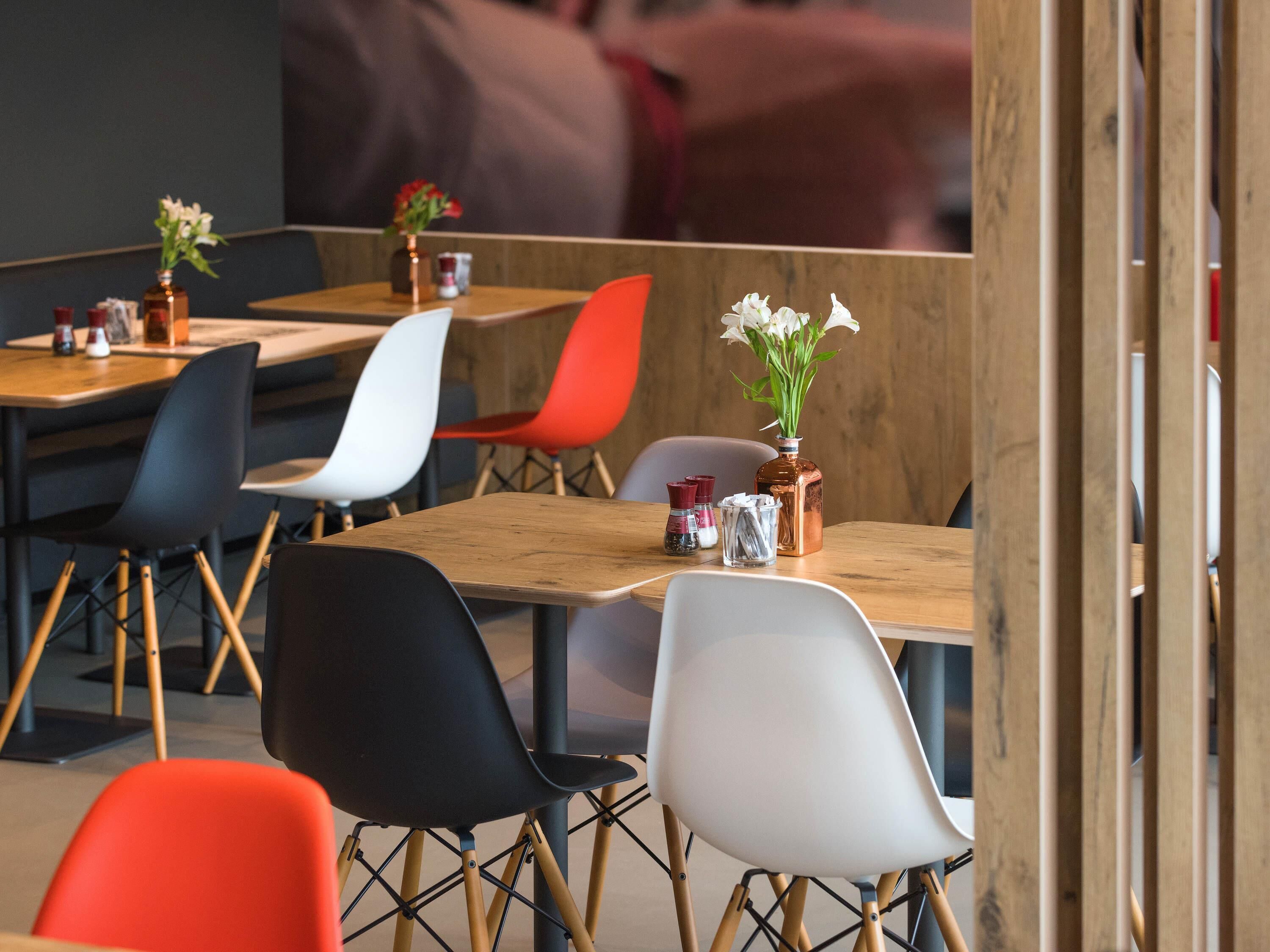 Un comedor moderno con mesas y sillas de madera, algunas con plantas.