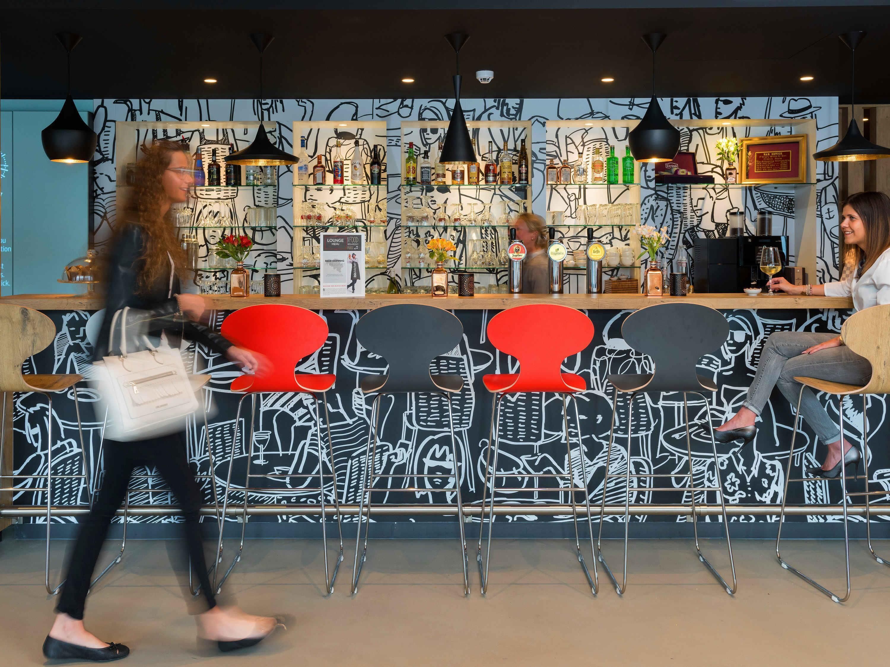 Zona de bar con mostrador, taburetes y una pared decorada con arte abstracto.