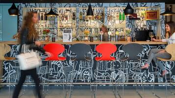Zona de bar con mostrador, taburetes y una pared decorada con arte abstracto.