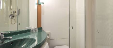 Un baño moderno con cabina de ducha de vidrio, un lavabo verde y un inodoro blanco.