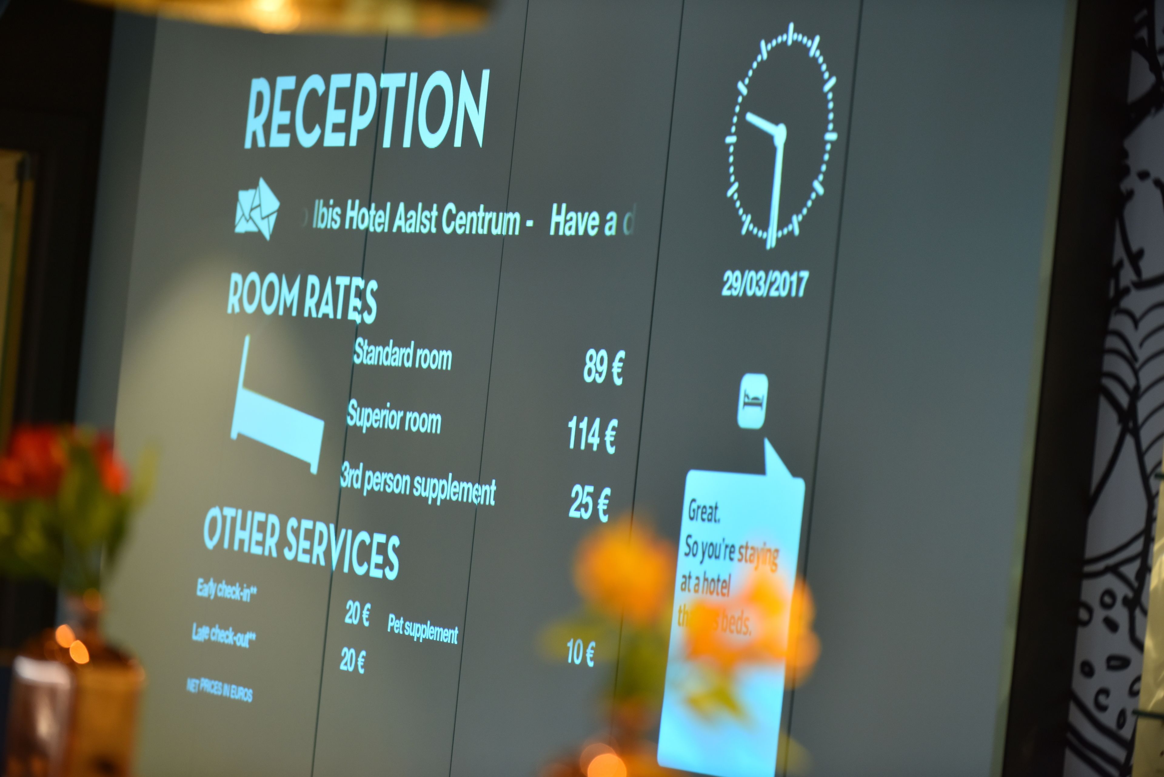 Een digitaal scherm met informatie over de receptie, zoals kamerprijzen en overige diensten.