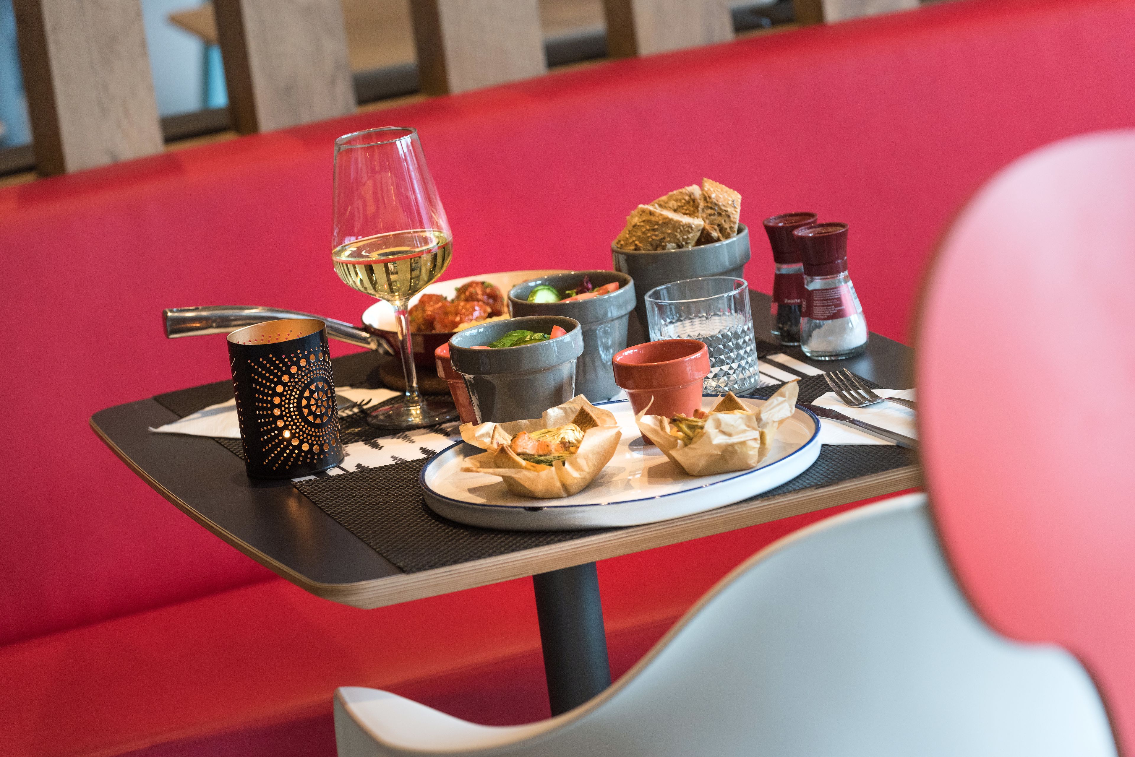 A dining table with various food items, a wine glass, and condiments.
