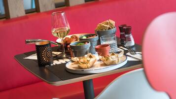 A dining table with various food items, a wine glass, and condiments.