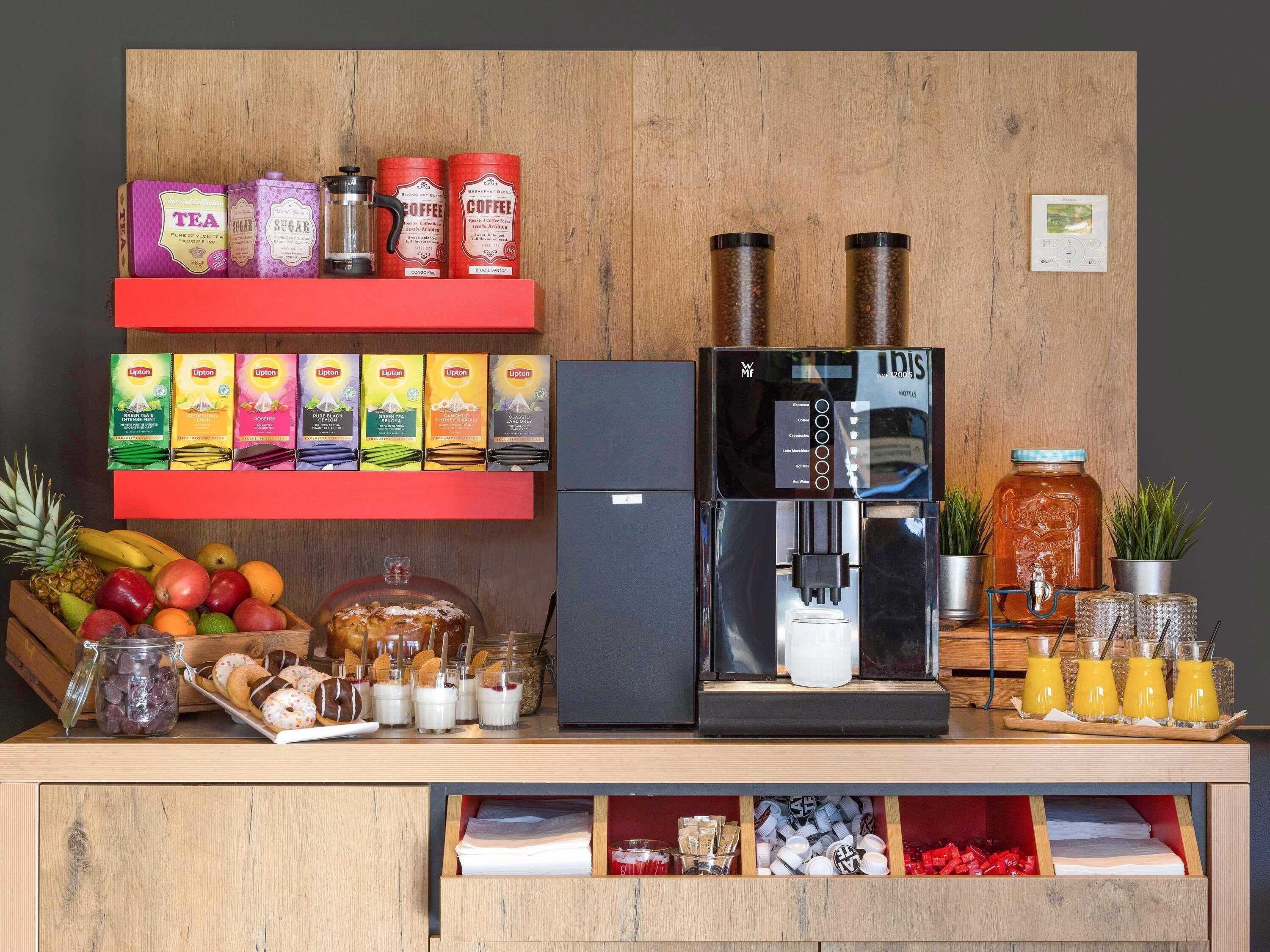Una estación de café con cafetera, té, azúcar y cajas de té Lipton.