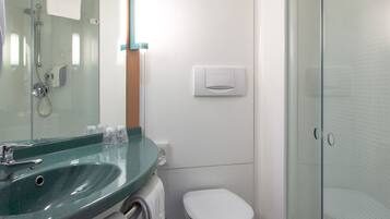 Une salle de bain moderne avec une douche à parois de verre, des toilettes blanches et un lavabo vert avec un miroir au-dessus.