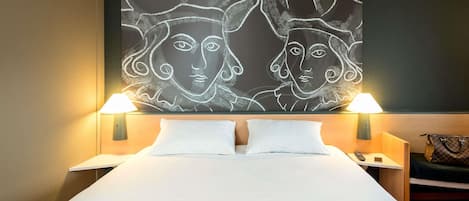 Habitación de hotel con cama, dos lámparas de noche, una mesita de noche, un bolso de mano y un cuadro abstracto de gran tamaño en la pared.