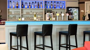 A bar area with multiple liquor bottles and glasses, bar stools, and a refrigerator. - ibis Aalst Centrum (Aalst)