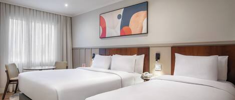 A hotel room with two beds, a desk, a chair, and a large abstract painting on the wall.