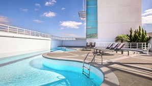 A rooftop swimming pool with a clear blue sky, lounge chairs, and a palm tree. - São Paulo Nações Unidas Affiliated by Meliá (São Paulo)