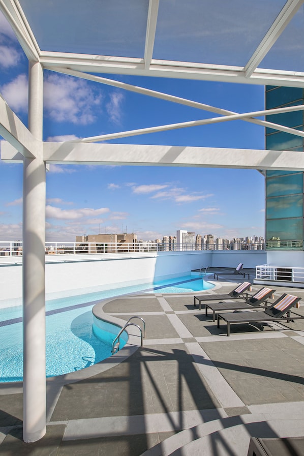 Una piscina al aire libre, sillones reclinables de piscina