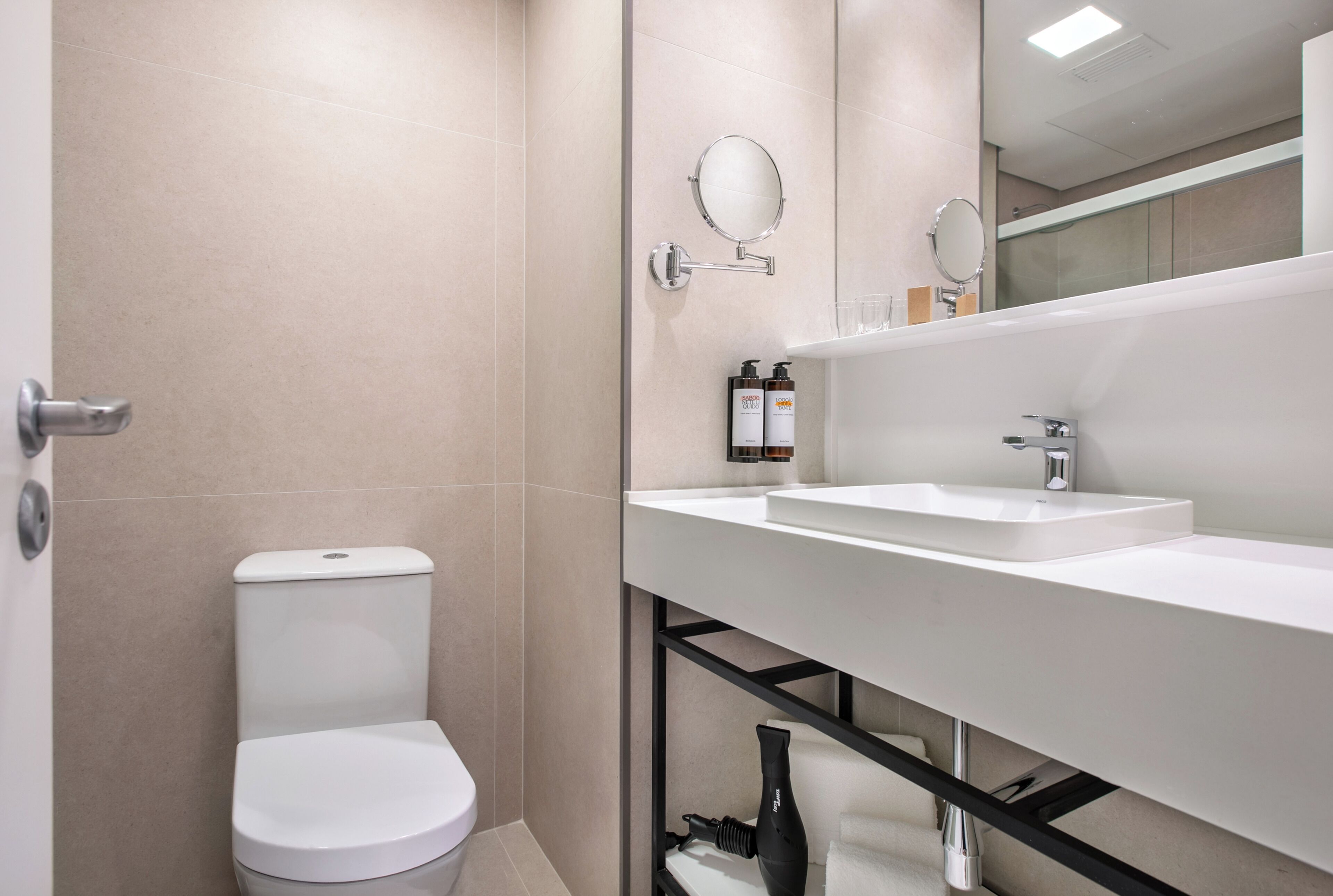 Ein modernes Badezimmer mit Toilette, Waschbecken und Spiegel.