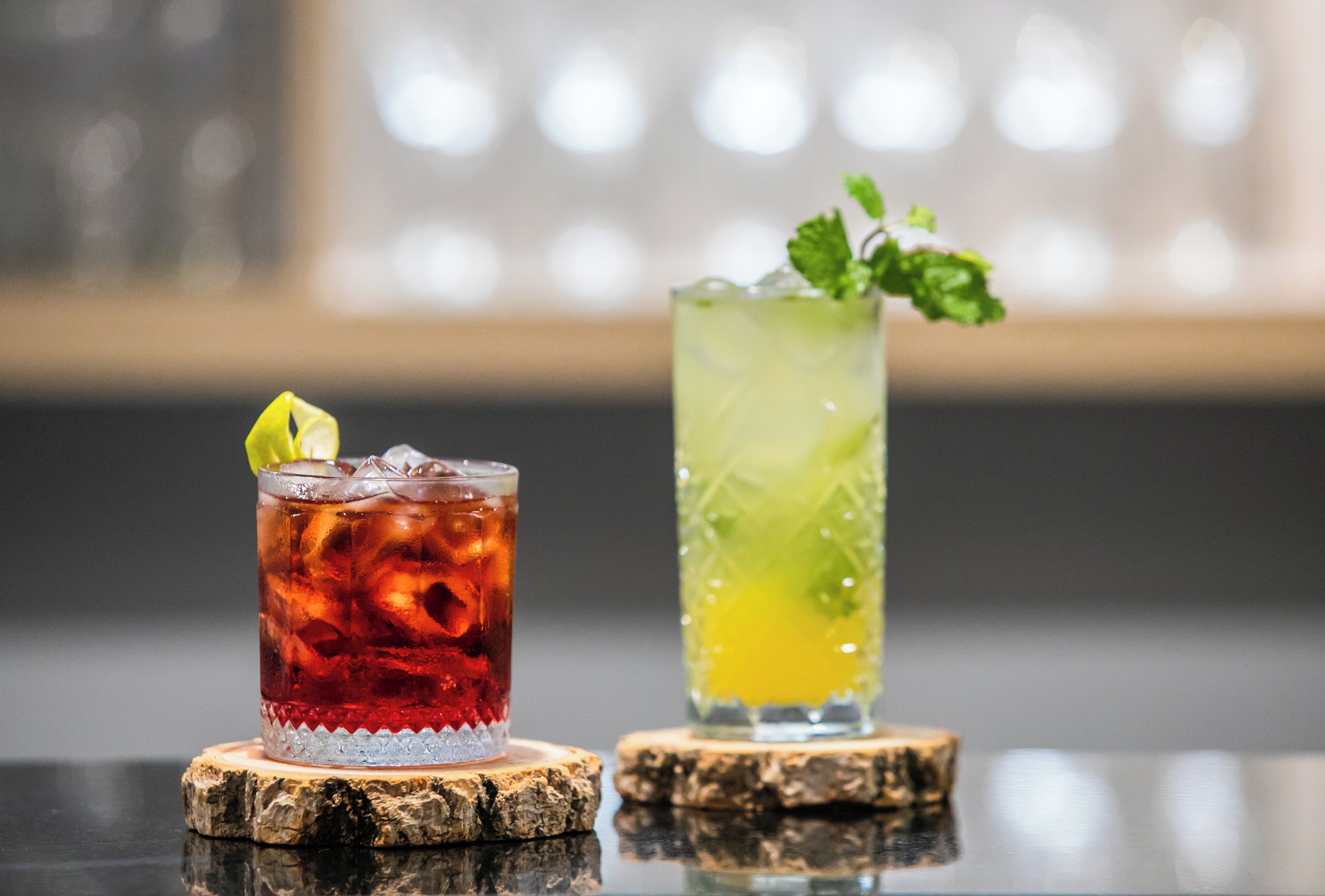 Two drinks on coasters with a blurred background.