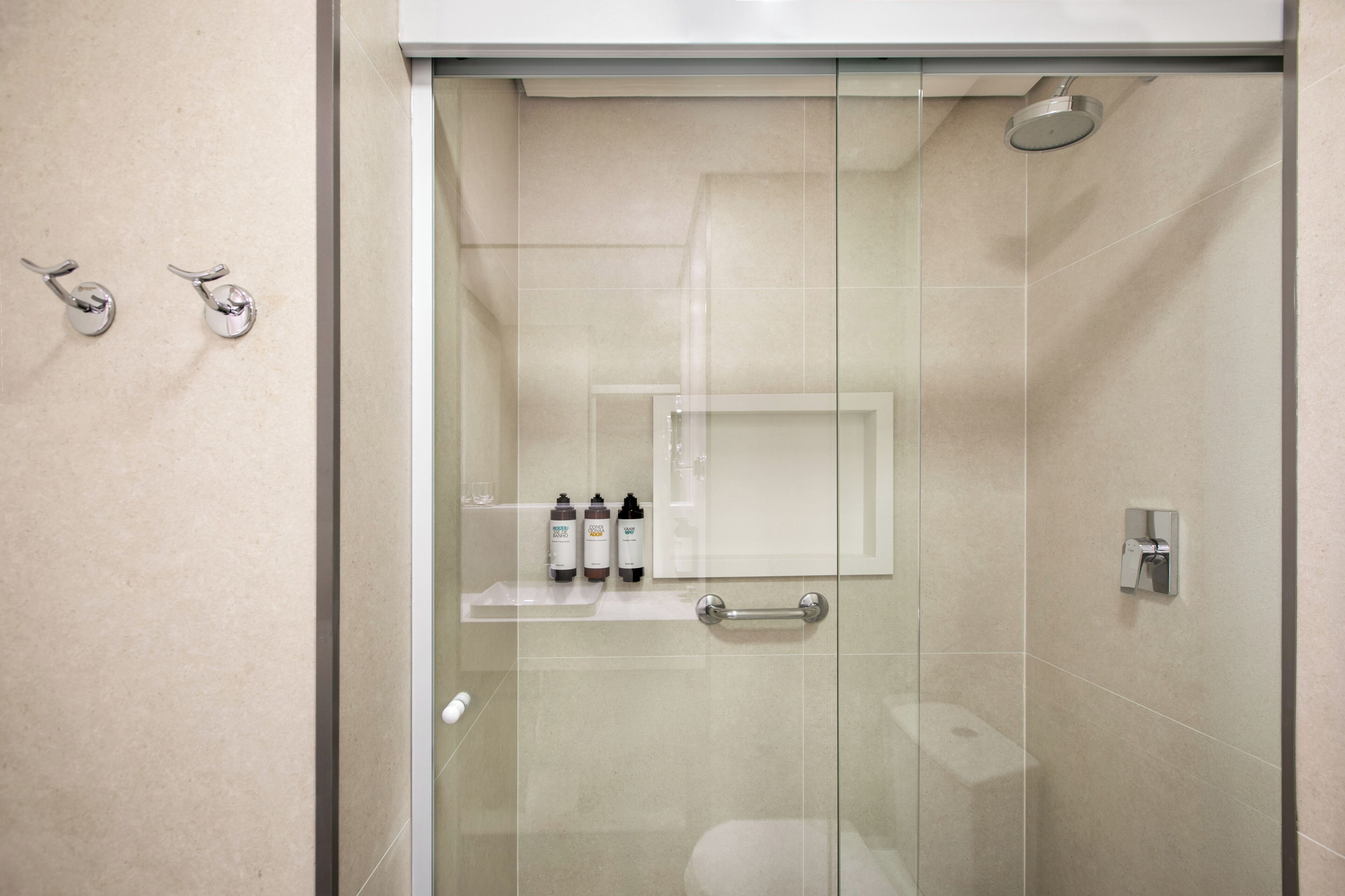 A modern bathroom with a glass shower enclosure, a toilet, and a shelf with toiletries.