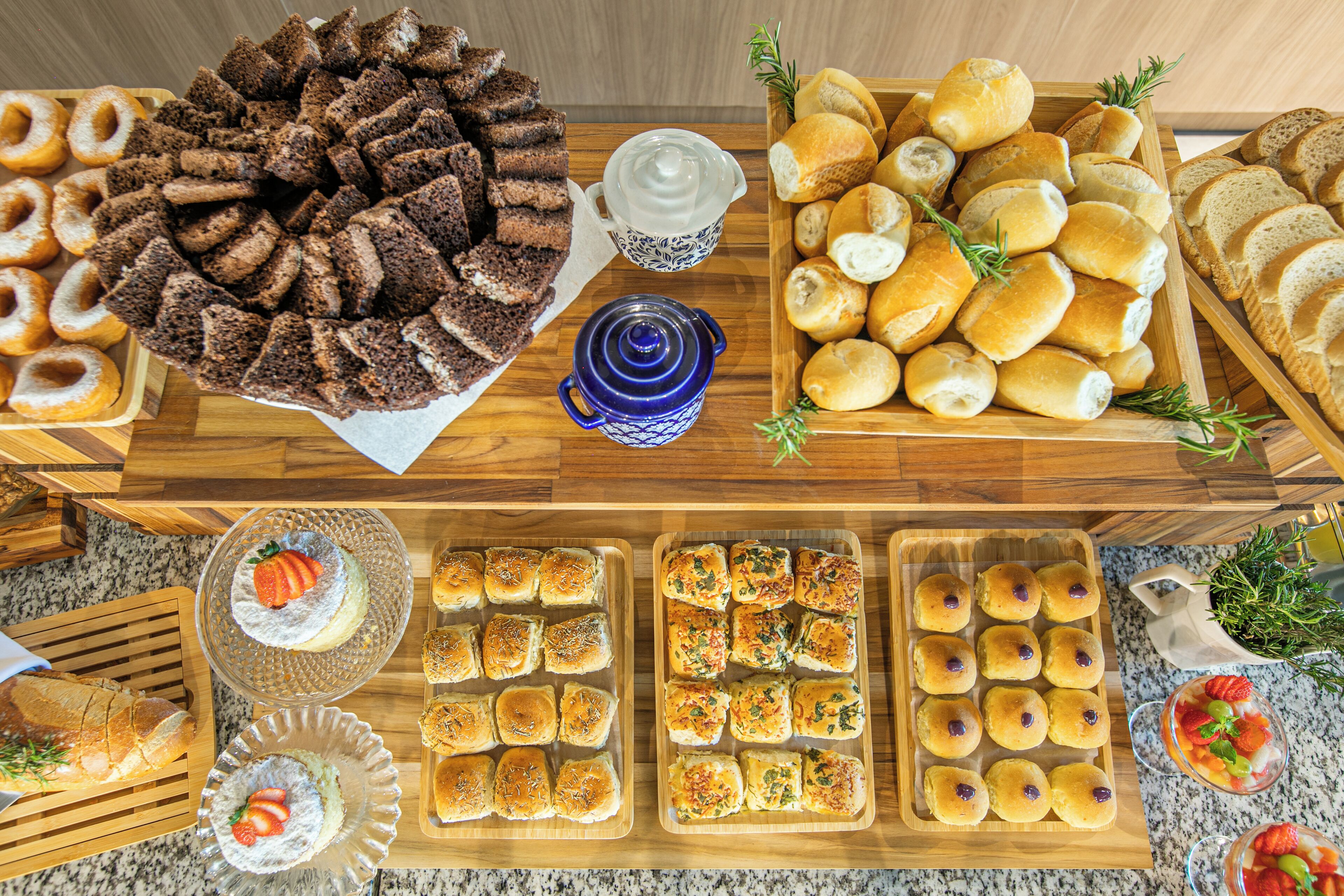 Una mesa de buffet con una variedad de productos horneados, incluyendo pan, bollos y pasteles.