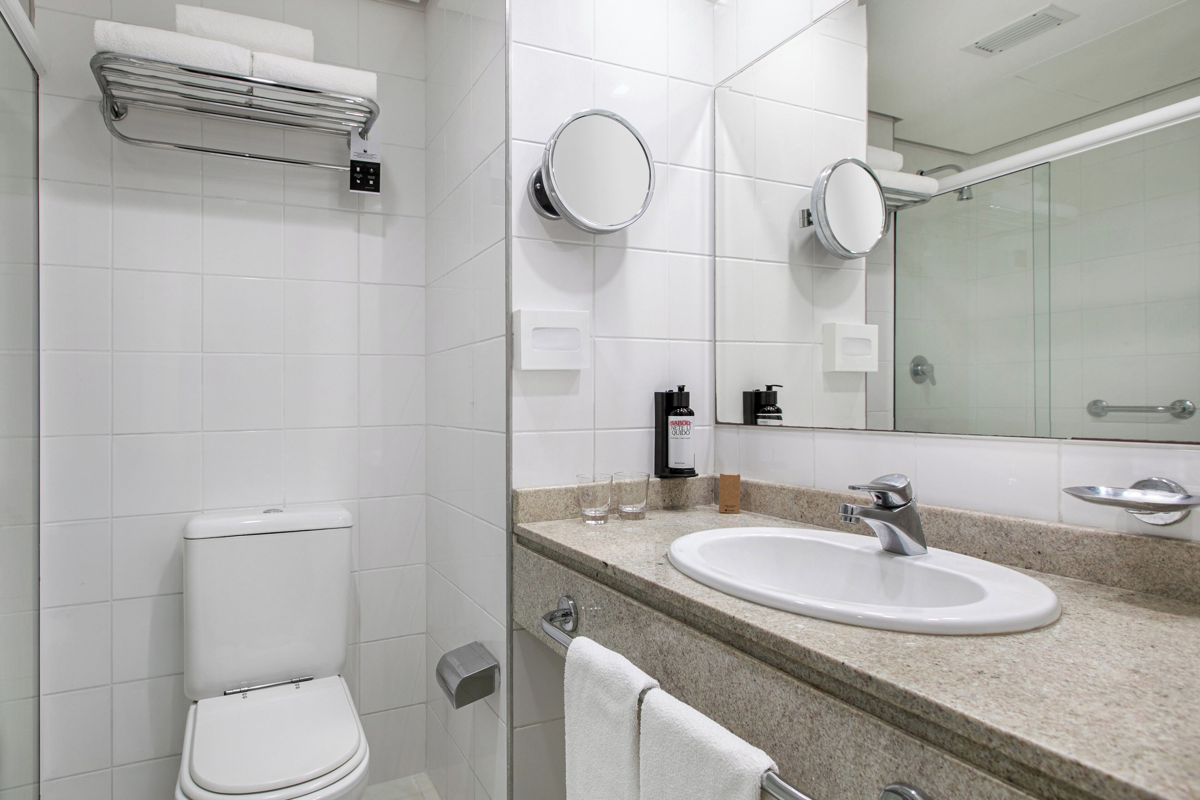 A modern bathroom with a toilet, sink, and mirrors.