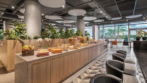 Un café moderno con una barra larga, zona de estar y amplios ventanales.