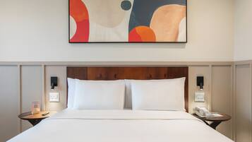 Quarto de hotel com uma cama grande, duas mesas de cabeceira, uma obra de arte na parede e uma cabeceira de madeira.
