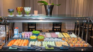 A buffet with various food items and beverages, including fruits, vegetables, and prepared dishes.