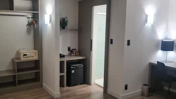 Un baño moderno con ducha, inodoro y lavamanos. Incluye un espacio de almacenamiento pequeño y un cubo de basura.