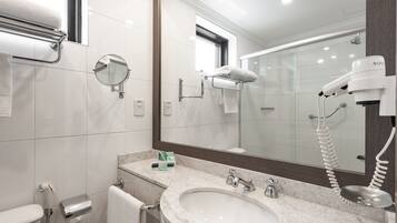 Un baño moderno con lavamanos, espejo, toallero y secador de pelo.
