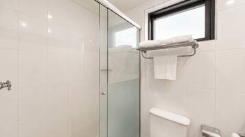 Un baño moderno con cabina de ducha de vidrio, inodoro y barra para toallas.