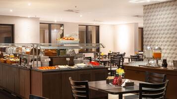 A buffet area with various food items and a seating area with tables and chairs.
