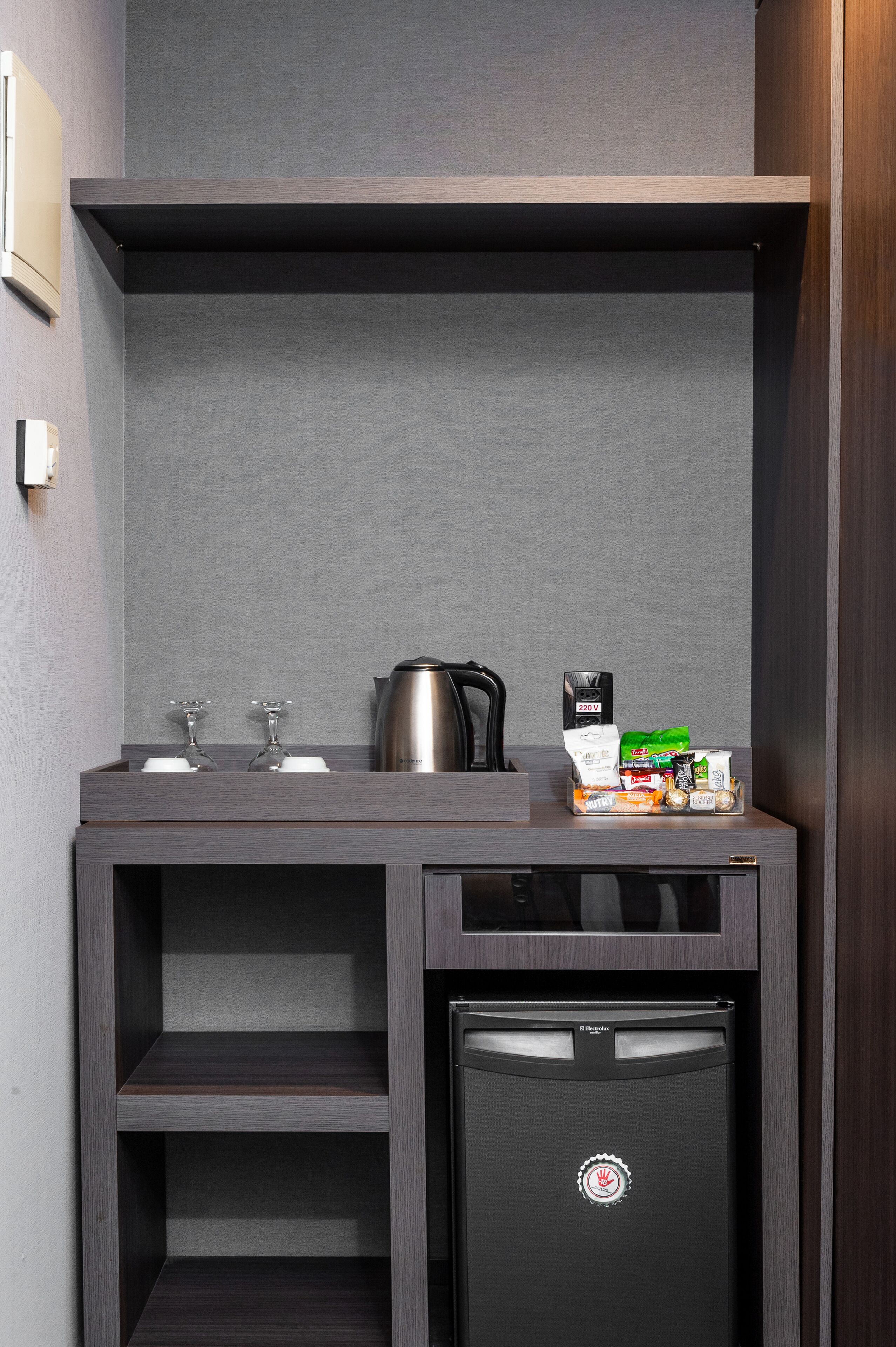 A compact kitchenette with a coffee maker, a kettle, and a small refrigerator.