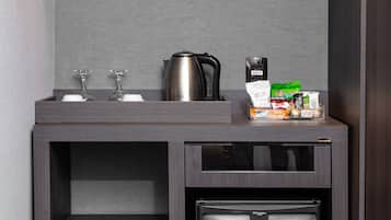 A compact kitchenette with a coffee maker, a kettle, and a small refrigerator.
