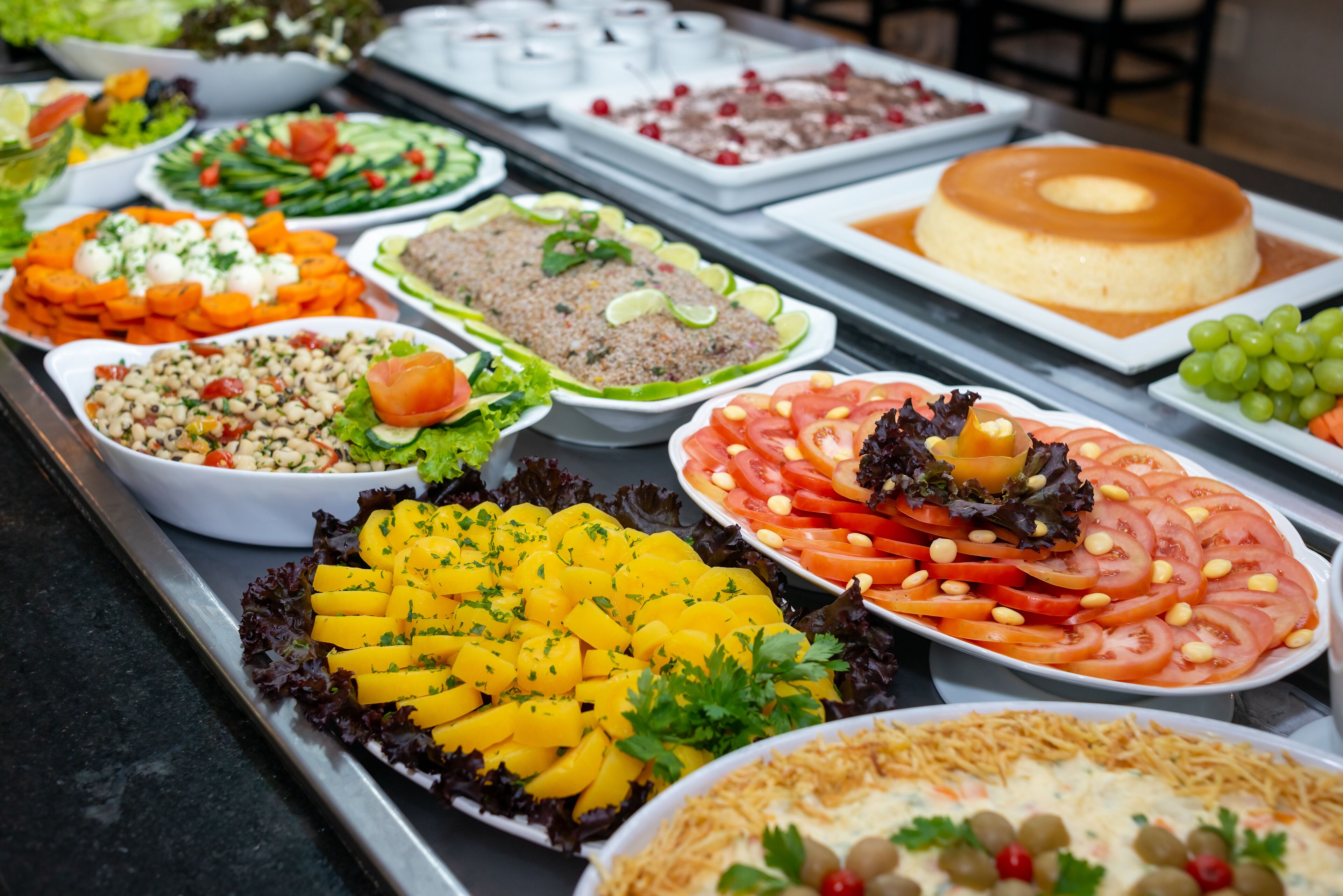 Un bufé con diversos platos, incluyendo ensaladas, frutas y un pastel.