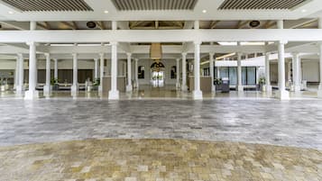 Un hall d’entrée spacieux, doté d’un haut plafond, de colonnes blanches et d’un sol à motifs.