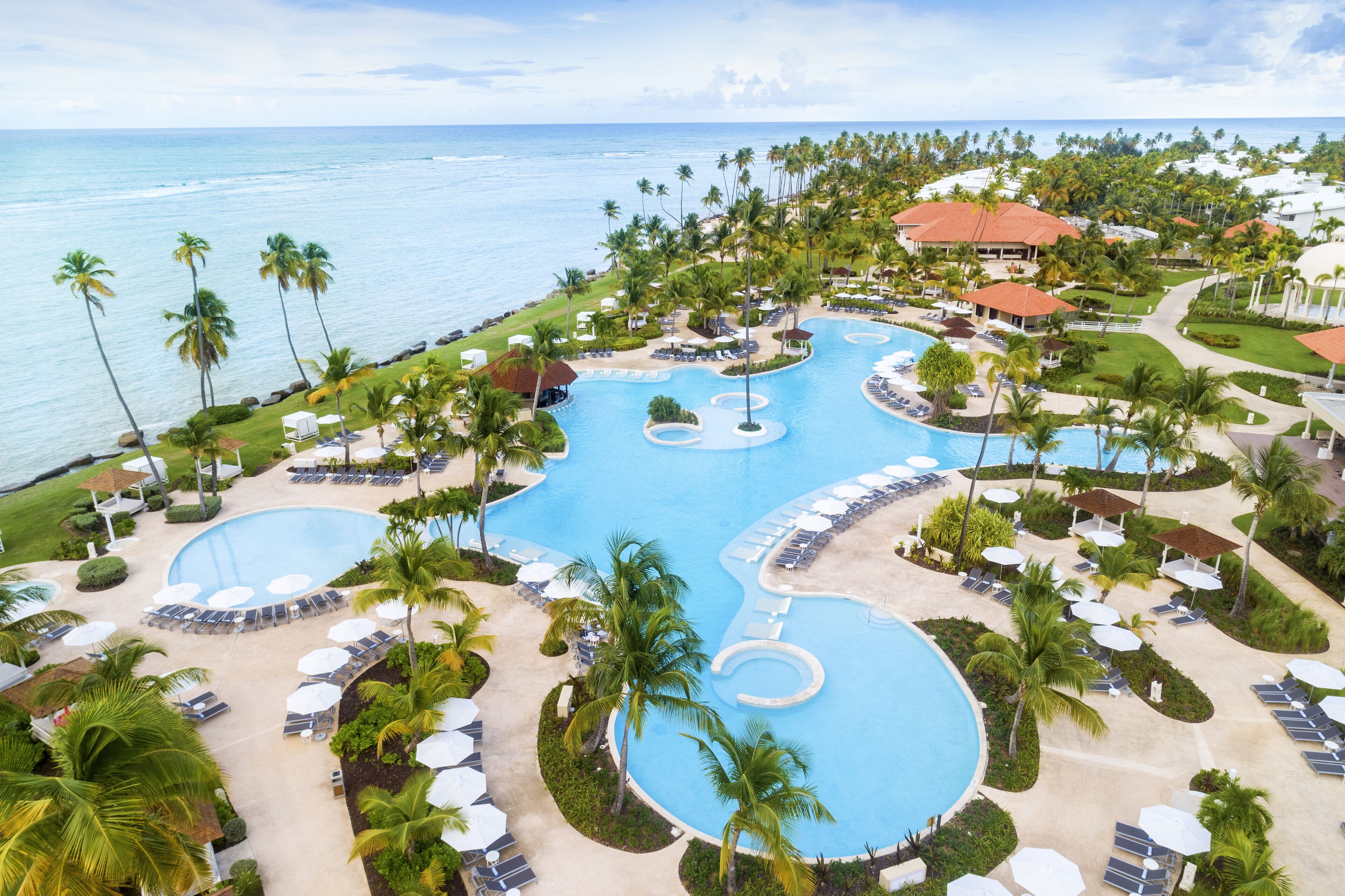 A resort with multiple swimming pools, palm trees, and beach views.