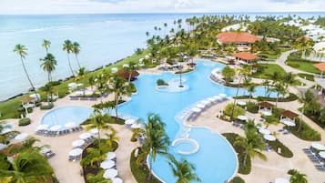 A resort with multiple swimming pools, palm trees, and beach views.