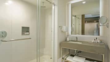 Un baño moderno con cabina de ducha de vidrio, tocador con lavamanos y espejo.
