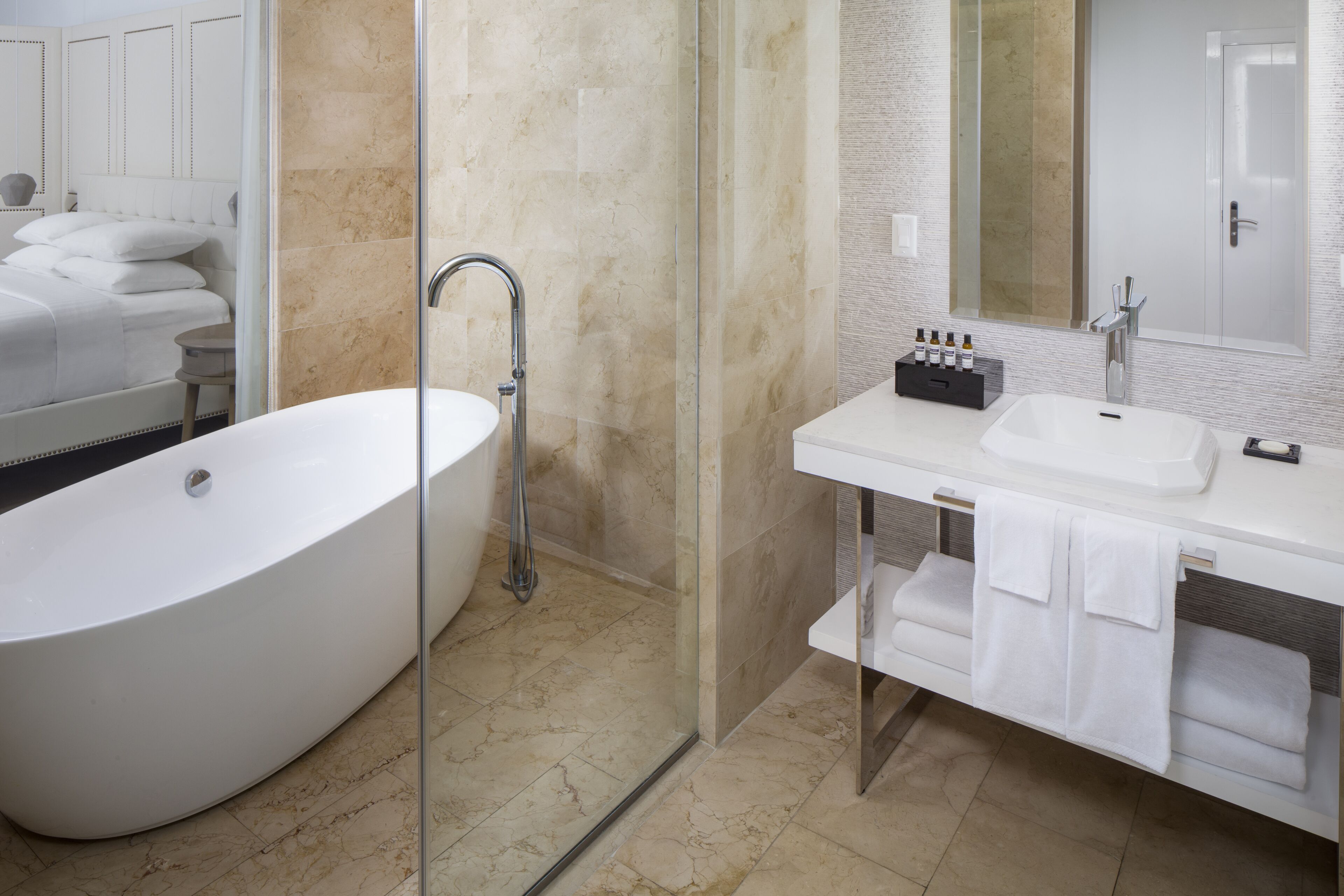 A modern bathroom with a freestanding bathtub, a glass-enclosed shower, and a vanity with a mirror and towel rack.