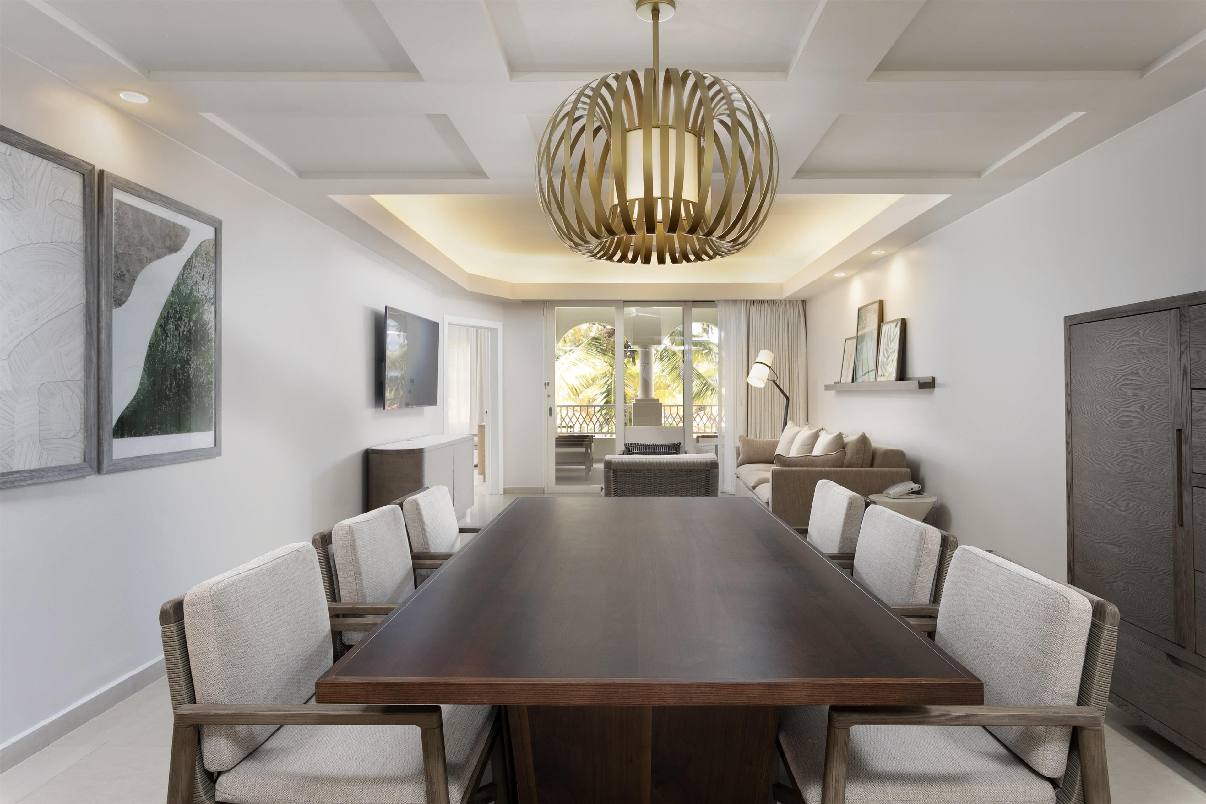 Un comedor moderno con una larga mesa de madera, sillas acolchadas y una lámpara colgante original.