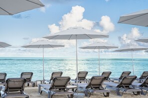 Am Strand, weißer Sandstrand, Liegestühle, Sonnenschirme