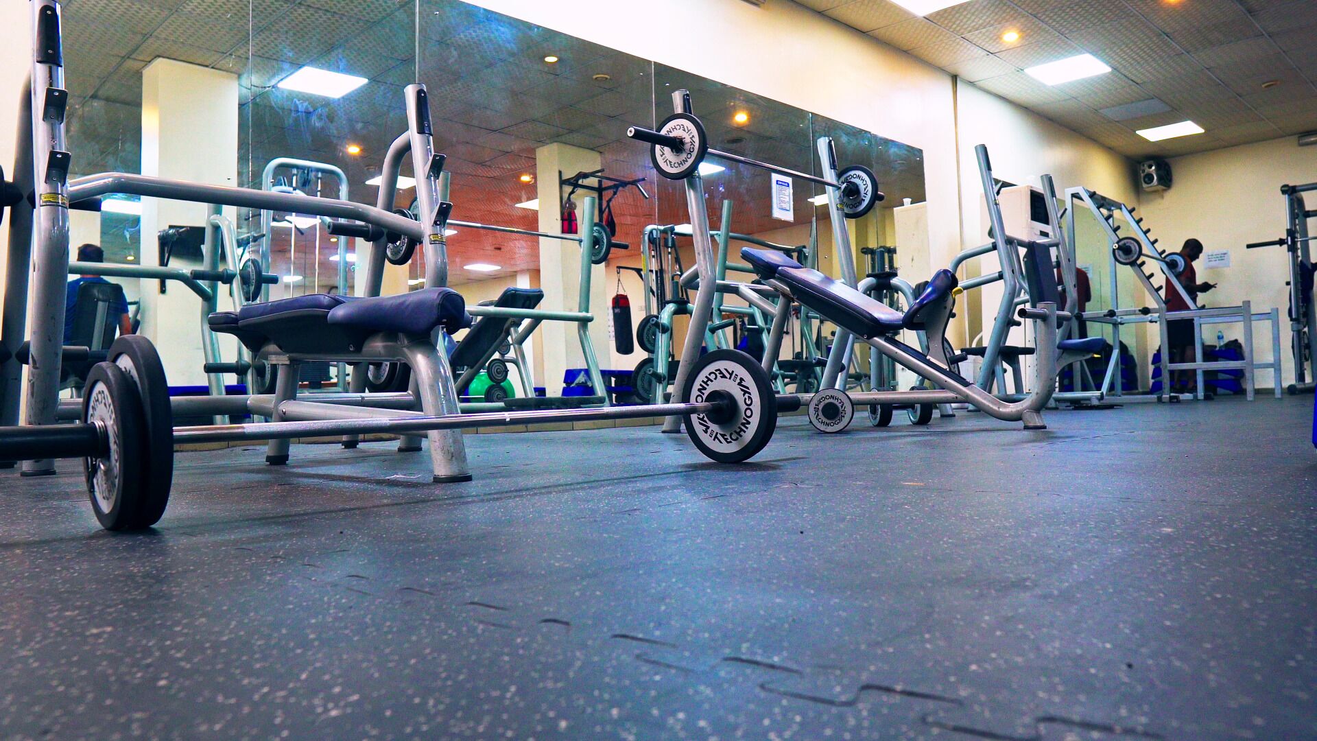 A gym with various exercise equipment, including a bench press and a leg press.