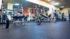 A gym with various exercise equipment, including a bench press and a leg press.
