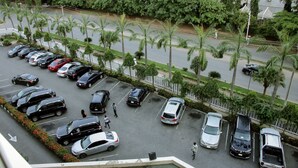A parking lot with multiple cars and a pedestrian walking. - Stratton Hotel Asokoro (Abuja)