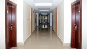 A corridor with wooden doors, a tiled floor, and a ceiling with recessed lighting. - Stratton Hotel Asokoro (Abuja)