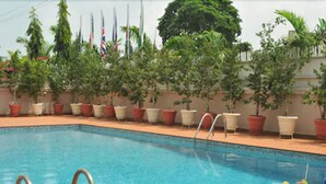 A swimming pool with lounge chairs and a table with drinks. - Stratton Hotel Asokoro (Abuja)