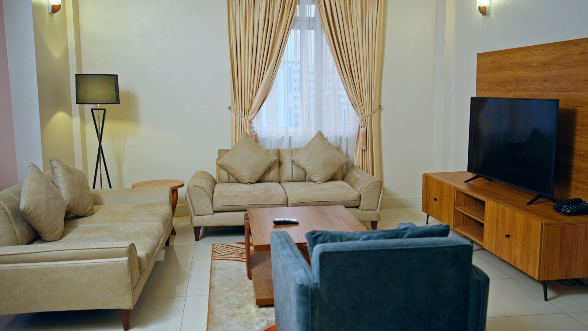 A living room with a sofa set, a coffee table, a TV on a wooden stand, and a floor lamp.