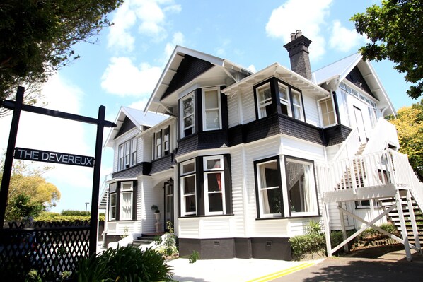 A large, multi-story house with a prominent front entrance and a staircase leading to the main door.