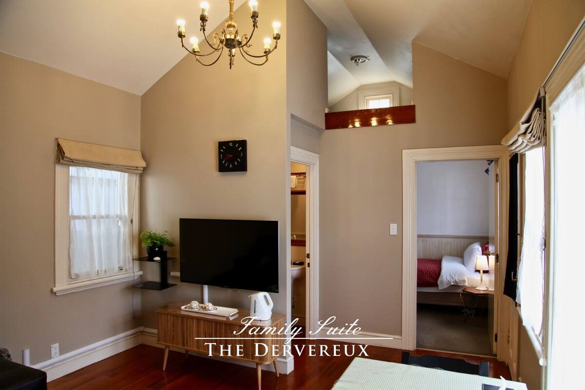 A family suite with a TV, wooden cabinet, and a chandelier.