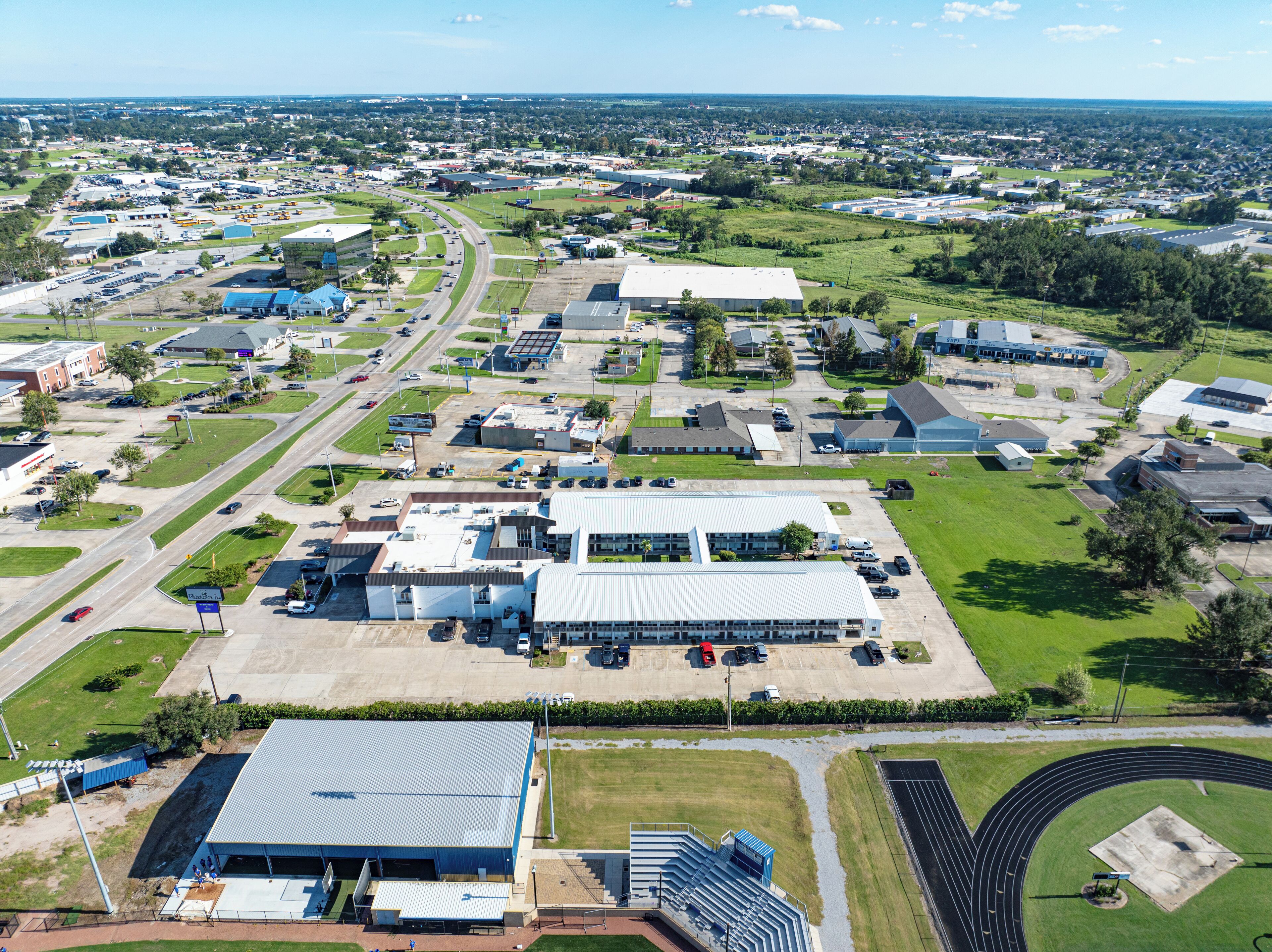 An aerial view of a commercial area with multiple buildings, roads, and green spaces.