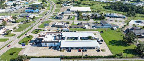 An aerial view of a commercial area with multiple buildings, roads, and green spaces.