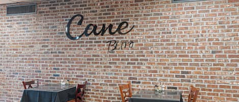 A brick wall with the words "Cane Bistro" and a table with chairs.